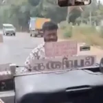 அரசு பேருந்து முன்புறம் தொங்கியபடி பயணி ஒருவர் செல்லும் காட்சி