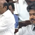 முன்னாள் அமைச்சர் எ.வ.வேலு சைகையில் பேசுகிறார், அவரை முதலமைச்சர் விஜய் புன்னகையுடன் கவனிக்கிறார்.
