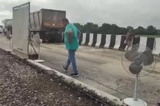 சாலையை உலர்த்த டேபிள் ஃபேன் வைக்கப்பட்டிருக்கும் காட்சி